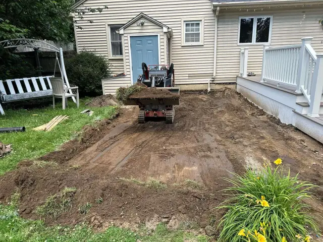Excavator regrading a backyard next to a deck