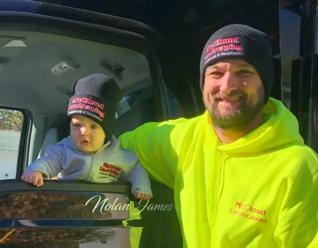 Jimmy of McCloud Landscaping in a hi-vis jacket with a young child in the truck
