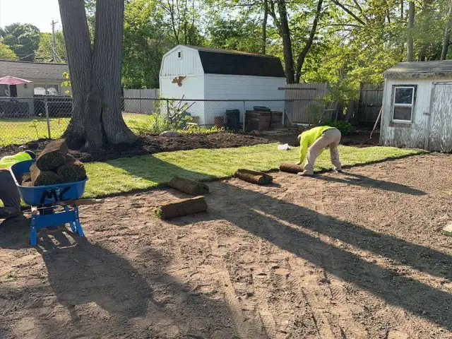 Crew member laying new sod on a prepared lawn