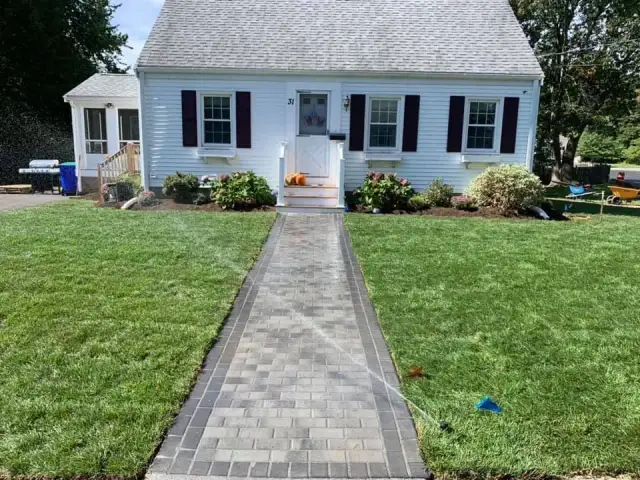 Paver walkway leading to a front door across a new lawn